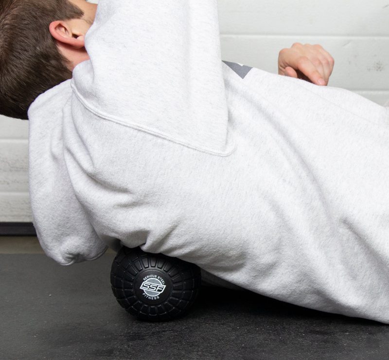 SSF Black Massage Ball In Use On Back On Black Mat Cropped 1